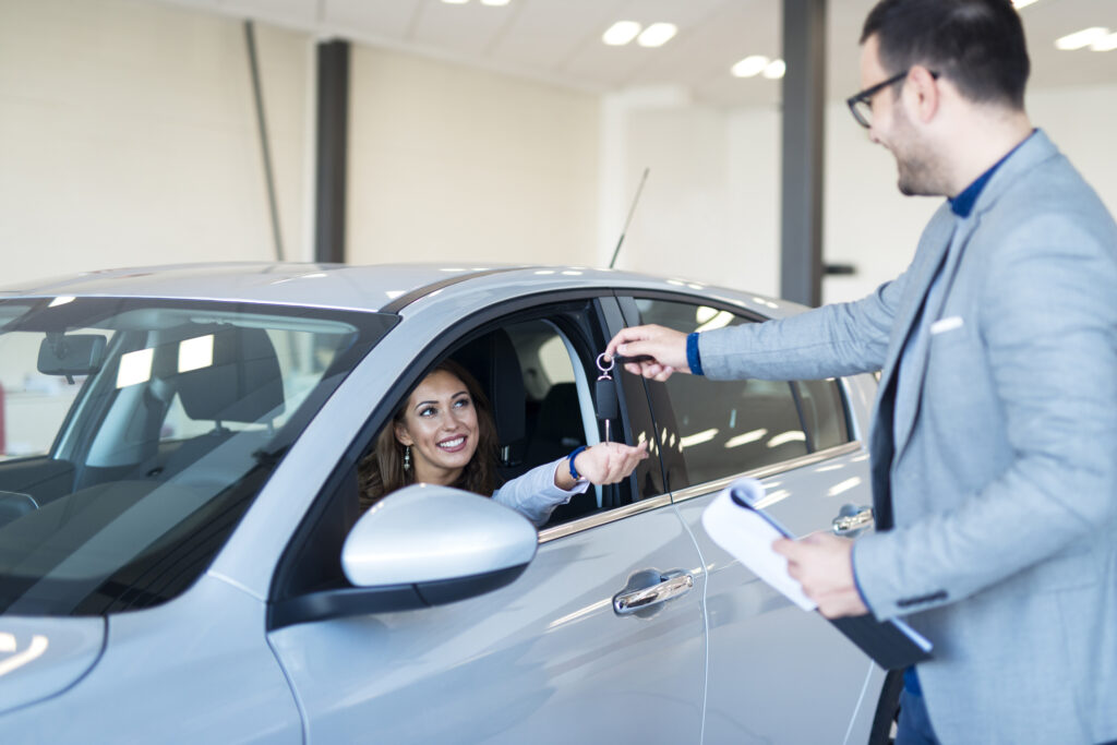 Vehicle dealer handing over keys to the new car owner.